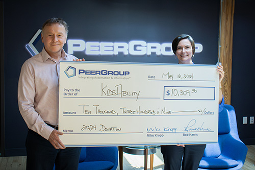 PEER Group CEO and Kidsability representation holding a donation cheque